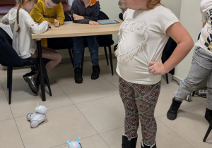 Dziewczynka stoi, a na podłodze są roboty