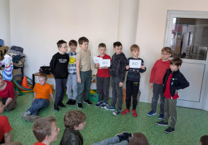 Chłopcy prezentują hasło, pozostałe dzieci siedzą na podłodze