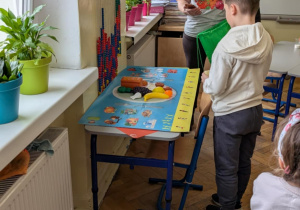 Chłopiec układa plastikową zabawkę na planszy