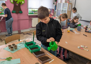 Chłopiec podlewa konewką rośliny