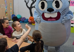 Dzieci siedzą, obok duża maskotka królika