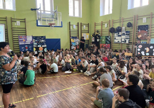 uczniowie siedzący na sali gimnastycznej