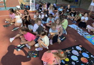 uczniowie prezentują prace na boisku szkolnym