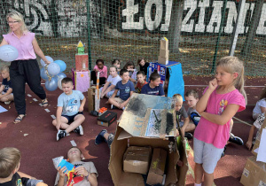 uczniowie prezentują prace na boisku szkolnym