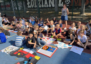 uczniowie prezentują prace na boisku szkolnym