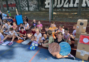 uczniowie prezentują prace na boisku szkolnym