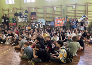 uczniowie siedzący na sali gimnastycznej