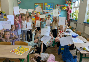 dzieci stoja w klasie trzymajac kartki