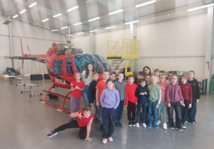 Uczniowie i nauczycielki stoją przed helikopterem