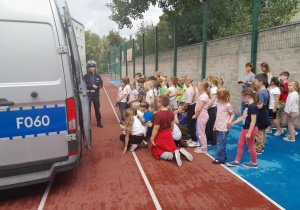 dzieci stoją na boisku słuchając policjantki
