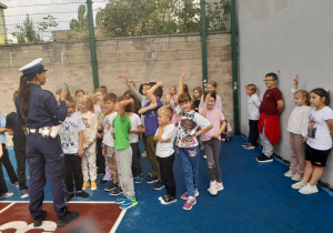 dzieci stoją na boisku słuchając policjantki