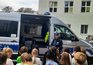 dzieci stoją przed radiowozem