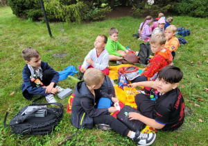 dzieci siedzą na trawie