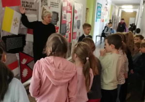 uczniowie stojący przy tablicy na holu szkoły