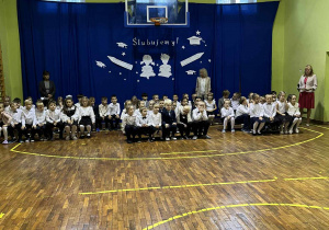 uczniowie siedza na sali gimnastycznej