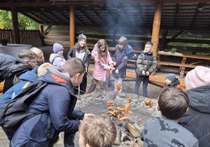 Uczniowie pieką kiełbaski na ognisku