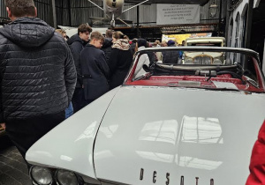 uczniowie stoja w fabryce samochodów