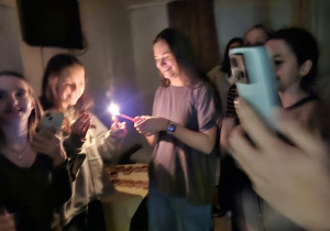 uczniowie zapalają świeczkę