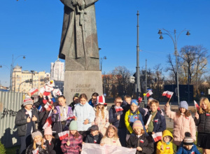dzieci pozują do zdjęcia pod pomnikiem marszałka Piłsudskiego