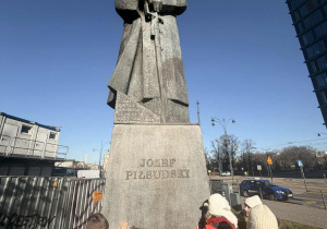 dzieci pozują do zdjęcia pod pomnikiem marszałka Piłsudskiego