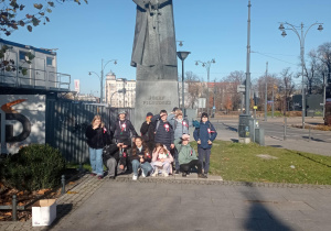dzieci pozują do zdjęcia pod pomnikiem marszałka Piłsudskiego