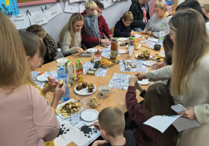 Rodzice z dziećmi siedza przy stołach