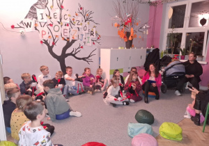 Uczniowie z nauczycielem siedzą słuchajac bajki