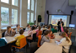 Uczniowie siedzą przy stołach w bibliotece