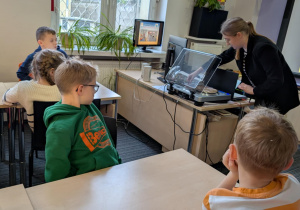 Uczniowie siedzą przy stołach w bibliotece