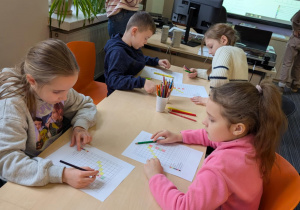 Uczniowie siedzą przy stołach w bibliotece
