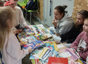 dzieci siedzą przy kiermaszu