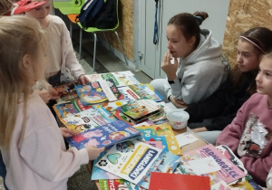 dzieci siedzą przy kiermaszu