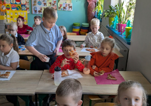 dzieci siedząc w ławkach jedzą pizze