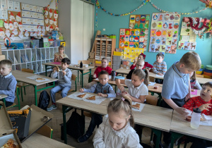 dzieci siedząc w ławkach jedzą pizze