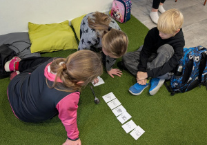 Dzieci siedząc na podłodze rozwiązują ekologiczne zdanie