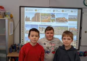 Mężczyzna z dziećmi siedzi na dywanie i objaśnia reguły gry