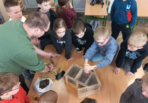 Dzieci i męźczyzna budują domek dla murarek