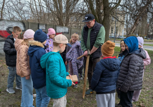 Dzieci i męźczyzna montują domek dla pszczół