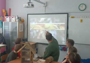 Dzieci i męźczyzna ogladają film przyrodniczy