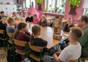 Dzieci i męźczyzna siedzą przy stołach