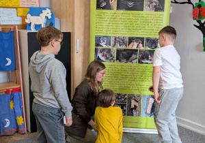 Chłopcy i kobieta oglądają plakat