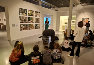 Uczniowie ogladają fotografie na wsytawie w muzeum_