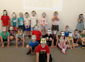 Dzieci w maskach stoja pod ścianą