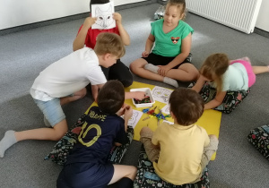 Kilkoro dzieci rysuje na podłodze
