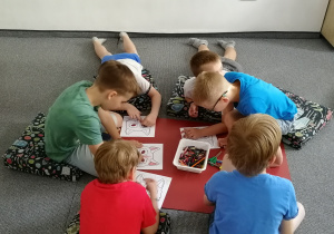 Kilkoro dzieci rysuje na podłodze