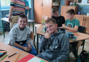 dzieci siedzą przy ławkach